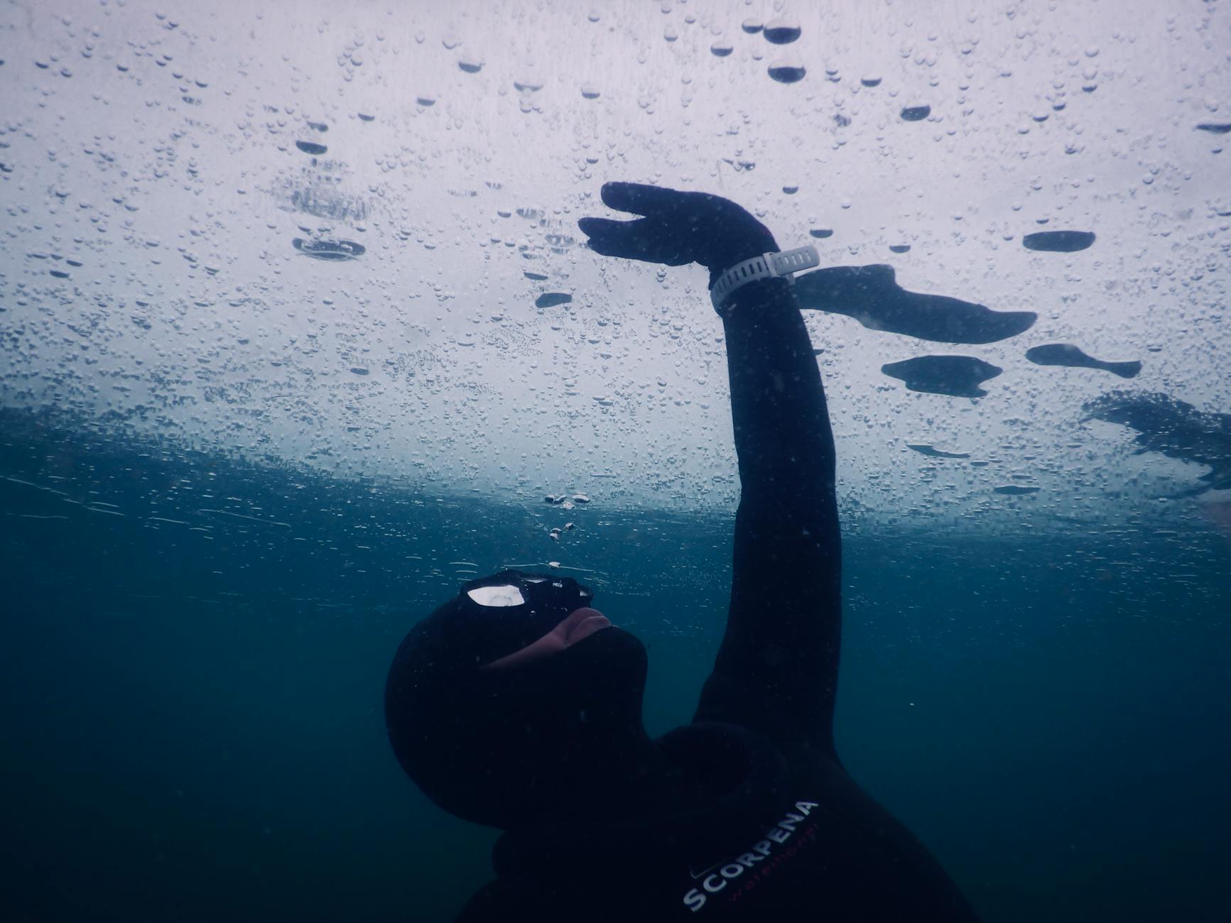 anonymous person swimming underwater during breath hold diving